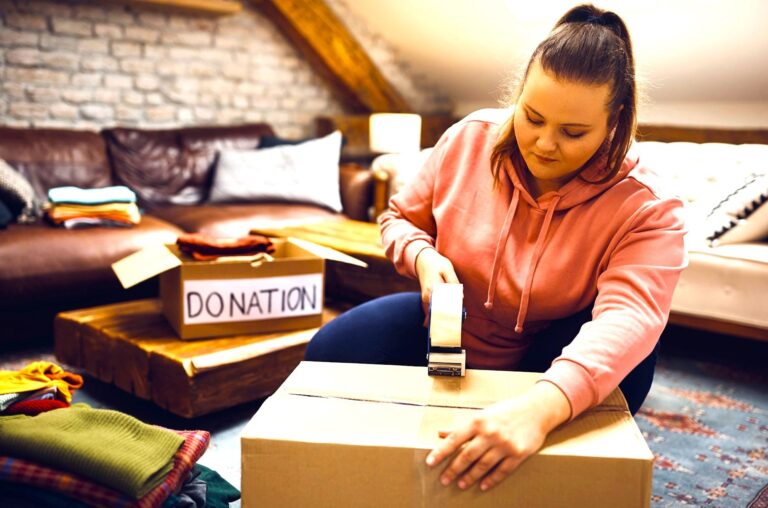 young woman sealing a box of donated items. Getty Images via Unsplash