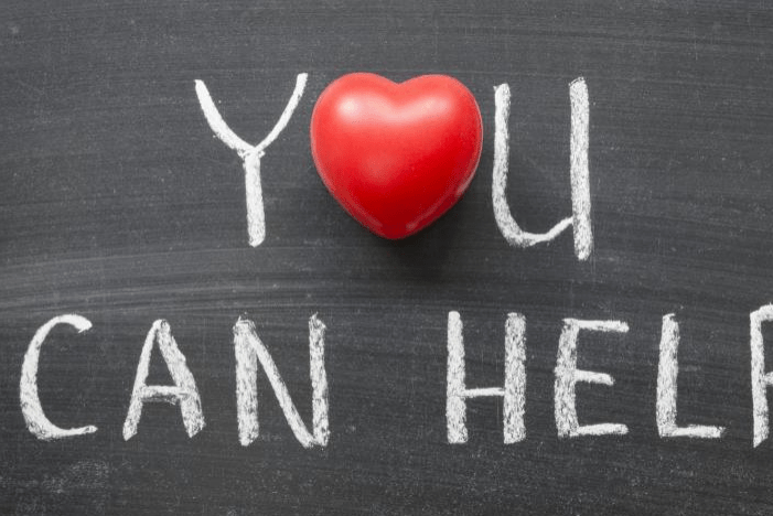 Red heart placed above the words "YOU CAN HELP" written in white chalk on a blackboard, symbolizing a call to action for support or assistance.
