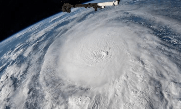 Satellite view of a powerful hurricane swirling in clouds above the Earth, showcasing its formidable structure and scale.
