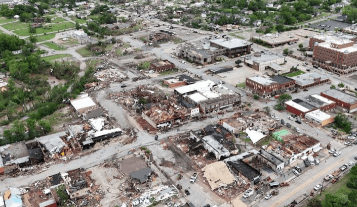 Aerial view of a devastated urban area, showing extensive destruction of buildings and debris, highlighting the impact of a recent disaster.