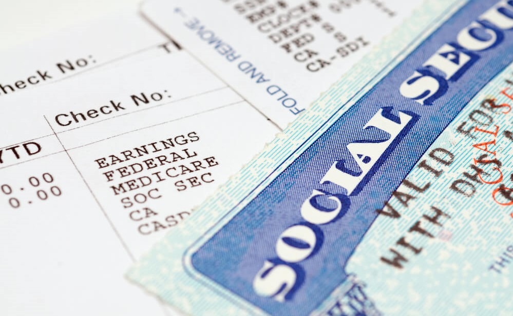 A Social Security card displayed alongside a pay stub, highlighting essential financial information and earnings details for record-keeping.