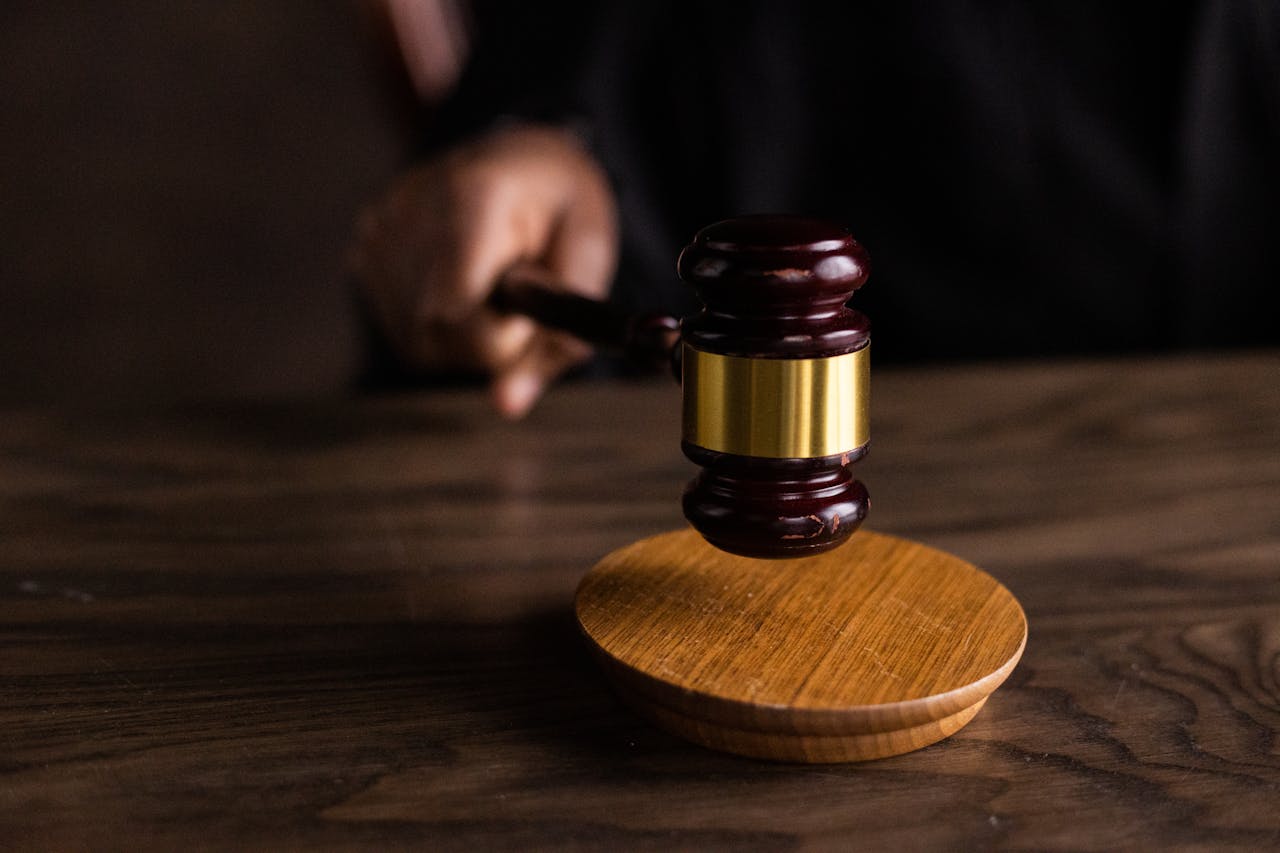 A gavel, poised above a round wooden block, symbolizes authority and decision-making in a legal context. Suitable for discussions on law and justice.