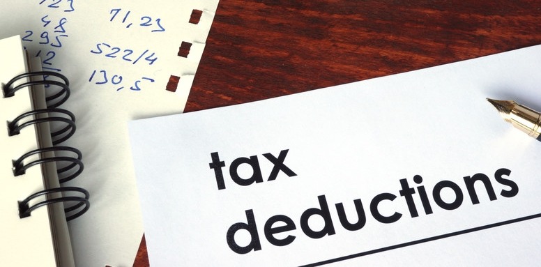Tax deductions document on a desk, accompanied by a notebook and a handwritten notepad with calculations, highlighting financial planning.