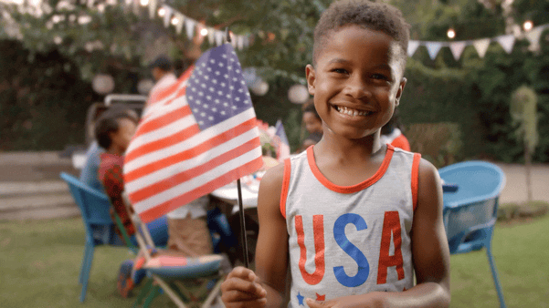 young boy waving US  flag at July 4 party